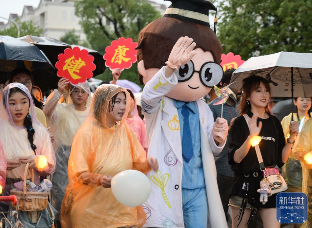 6月21日,酷爱成人网
学生在校园里冒雨巡游。2